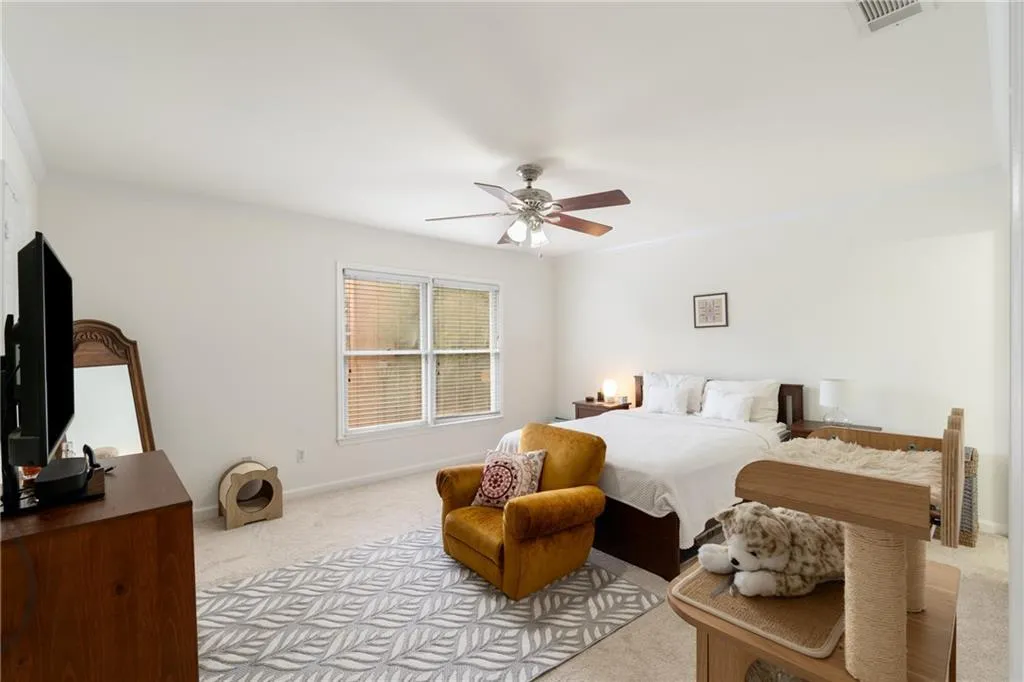 Carpeted bedroom with ceiling fan and crown molding