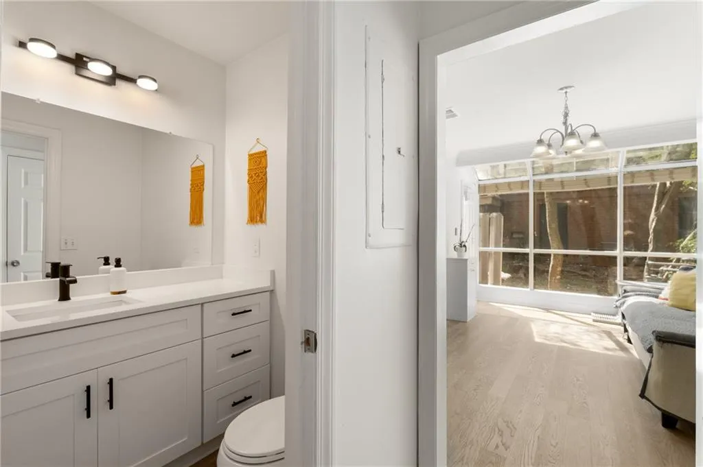 Bathroom with electric panel, vanity, wood-type flooring, an inviting chandelier, and toilet