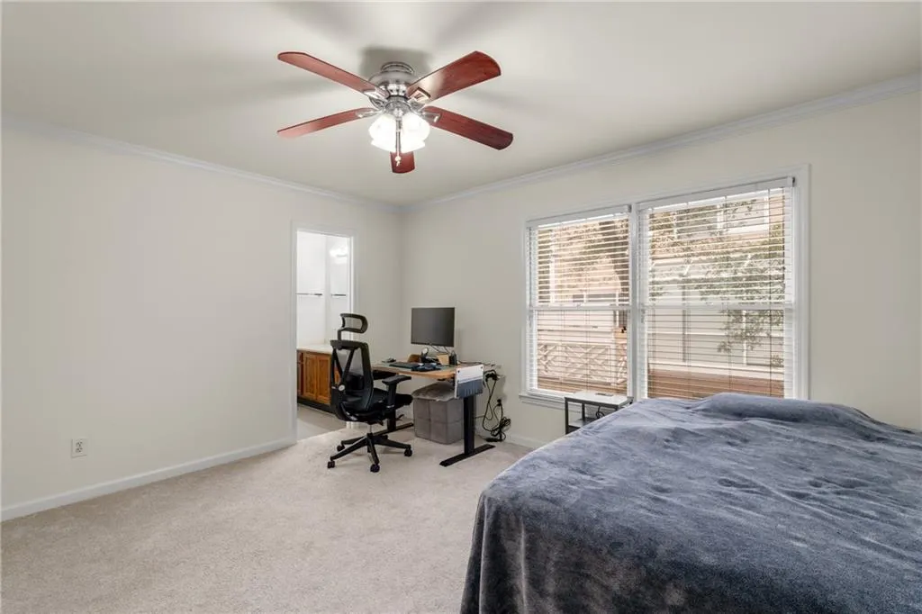 Bedroom with ceiling fan, light colored carpet, and crown molding