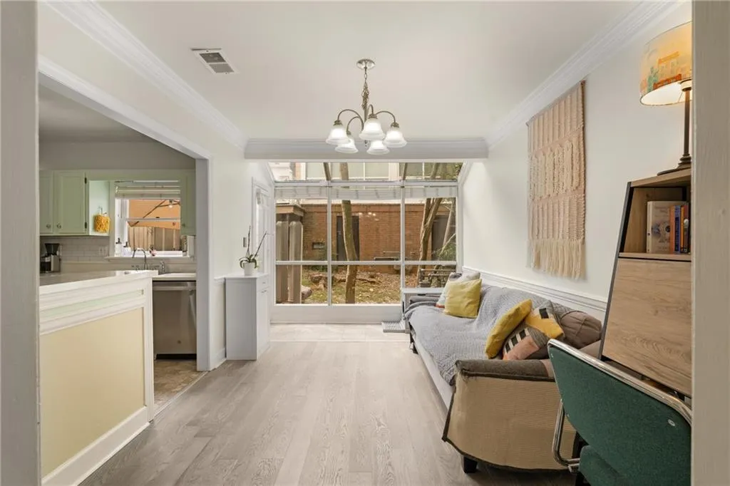 Living room with crown molding, a chandelier, and light hardwood / wood-style flooring
