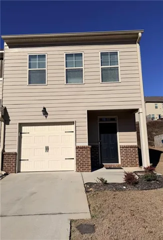 Siding exterior with brick accents, single-car garage with carriage-style door, covered entry, and upper-level windows