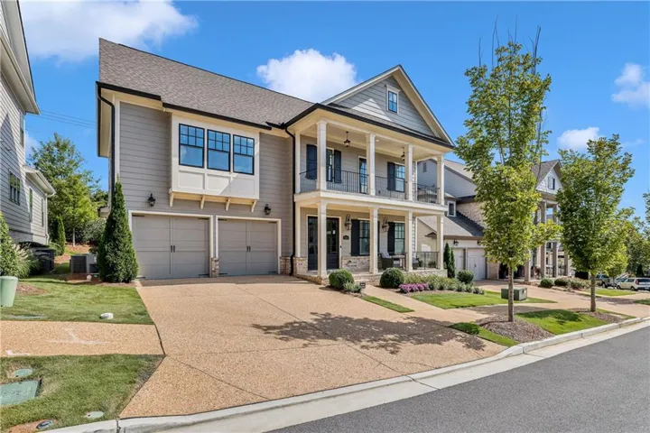 Multi-level property featuring a two-car garage, upper and lower covered balconies, and a stone and siding exterior
