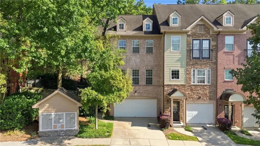 Multi-story exterior featuring brick, stone, and siding finishes, dormer windows, and attached garages
