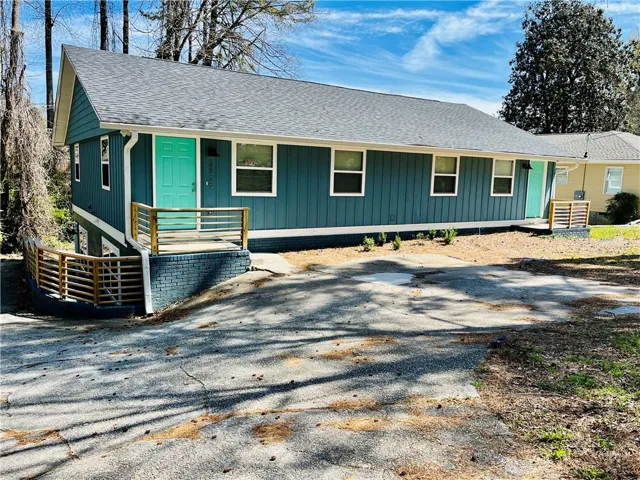 Contemporary exterior with vertical siding, a striking teal entry door, and a contrasting gray roof