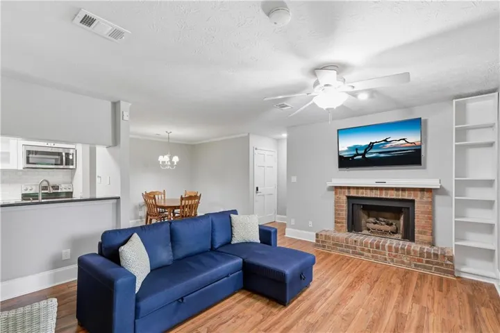 Living area featuring wood-finish flooring and a brick fireplace with a white mantel