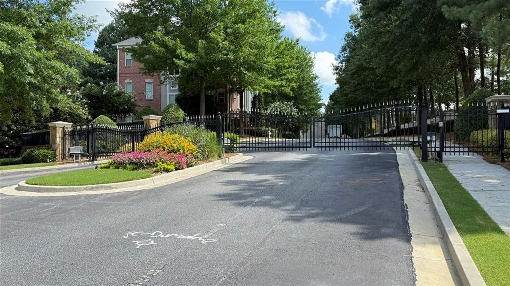 View of asphalt road featuring a gate, curbs, and a gated entry