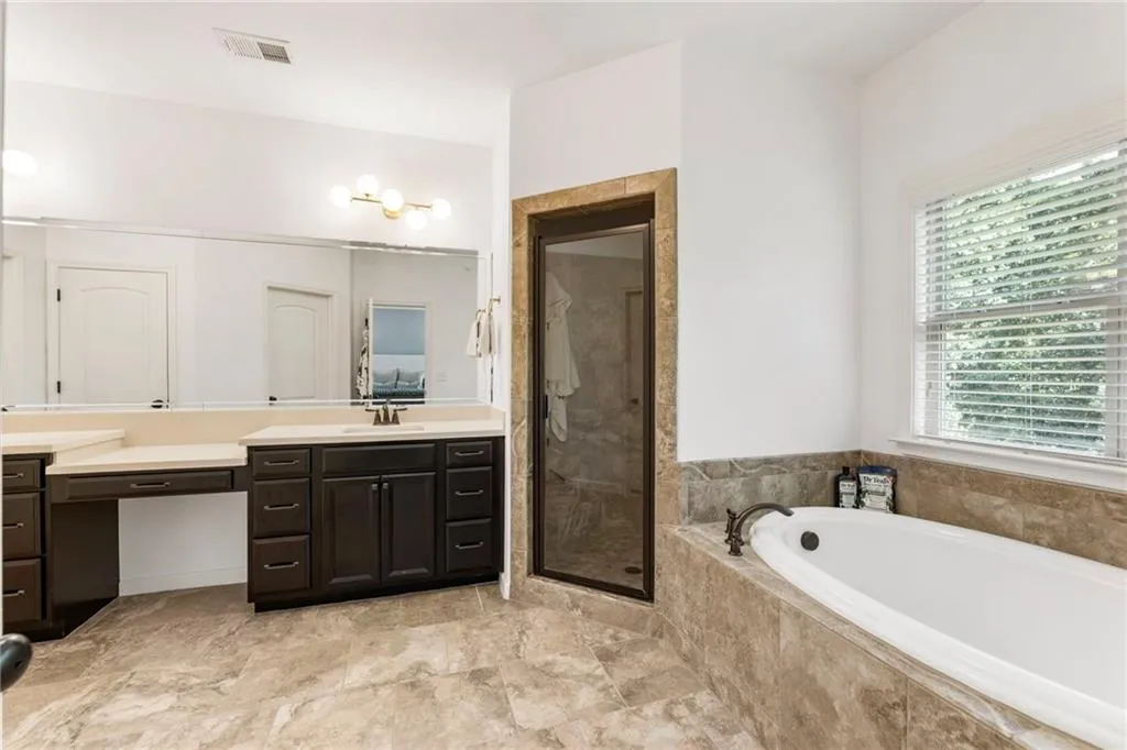 Bathroom featuring vanity, a bath, and a shower stall