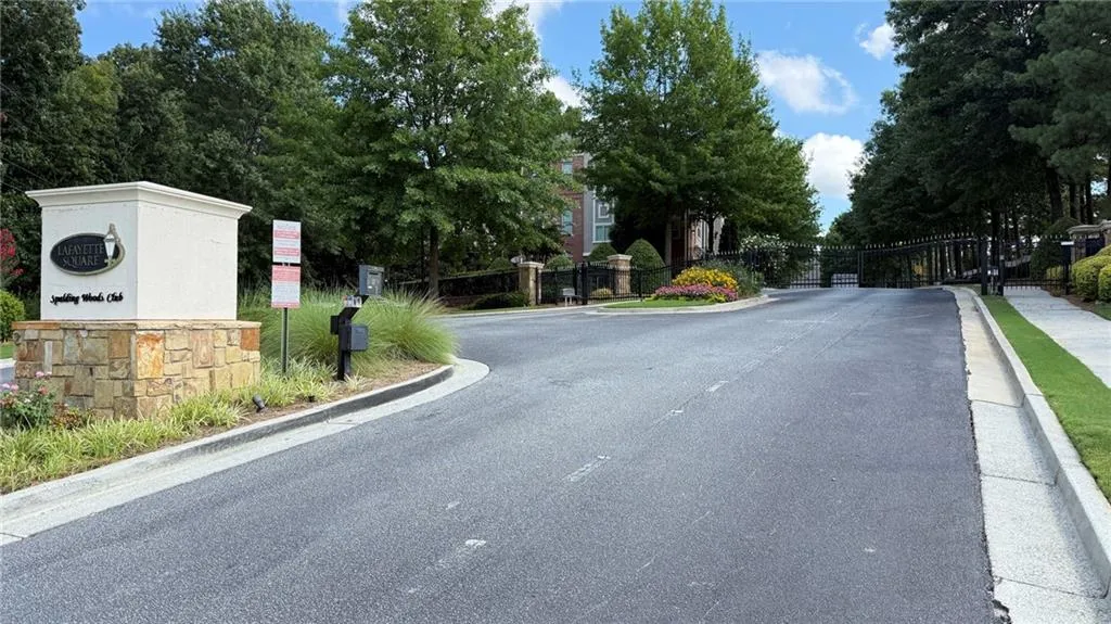 View of asphalt street with curbs, a gate, and a gated entry