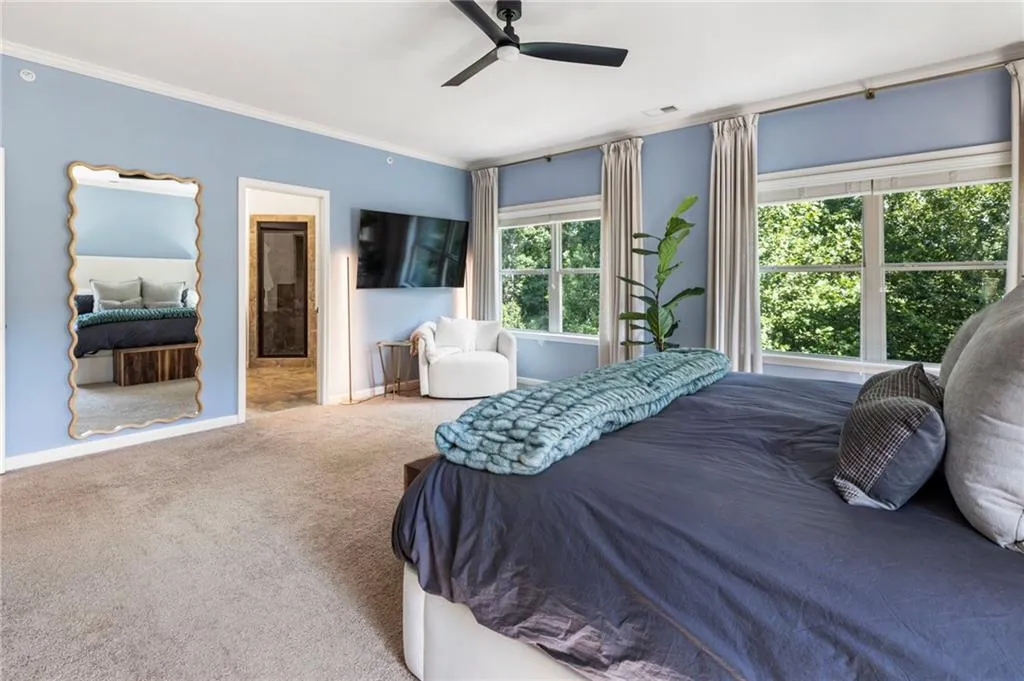 Bedroom with carpet, crown molding, a ceiling fan, and ensuite bath