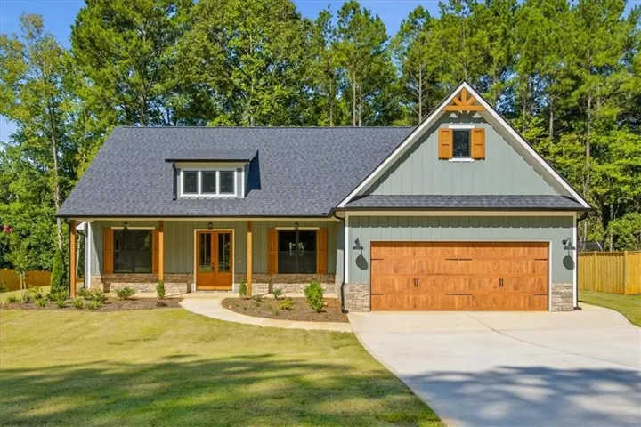 Craftsman-style exterior with a dark shingle roof, light green siding, and stone accents