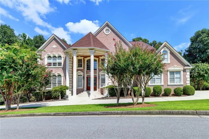 Brick exterior with a grand two-story portico, intricate window details, and a dark wood front door