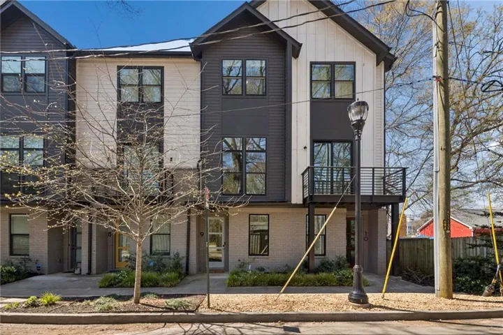 Modern townhome facade featuring white vertical siding, dark horizontal siding, and light brick accents