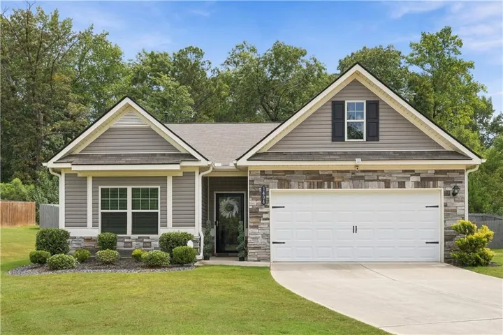 Craftsman-style exterior featuring a prominent gable roofline, stacked stone veneer, horizontal siding, and an attached two-car garage