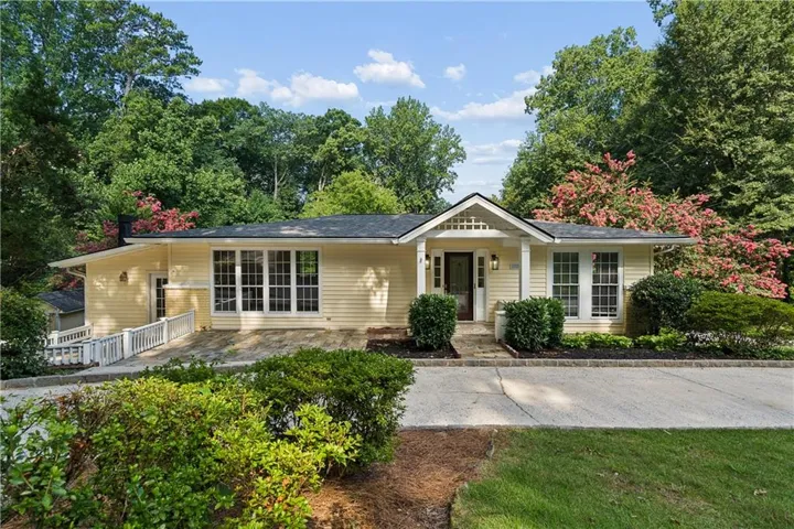 Single-story residence featuring light yellow siding, a covered entry with white columns, and a dark front door