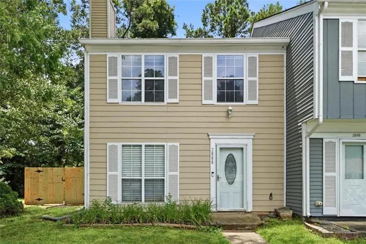 Two-story exterior with horizontal siding, multiple windows with white shutters, and a front entry door featuring an oval glass insert