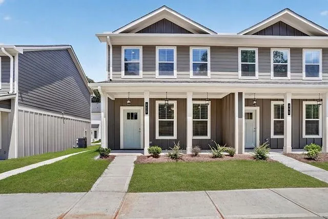 Contemporary townhome exterior featuring gray vertical and horizontal siding, white trim, and a light blue front door