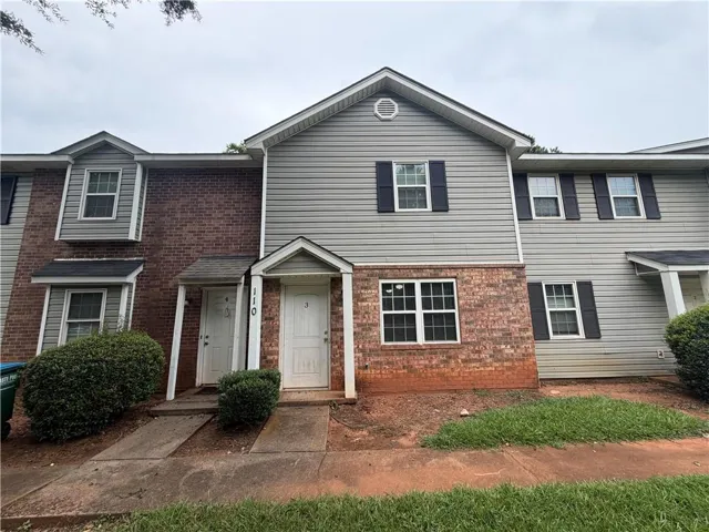Exterior featuring brick and siding facade, covered entry, and black window shutters