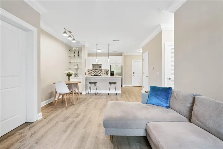 Living area with ornamental molding, light wood-style floors, and track lighting