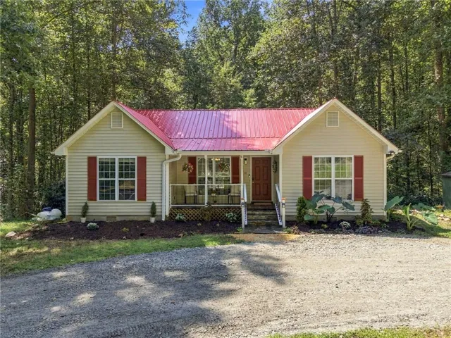 Light-colored siding exterior with a vibrant red metal roof