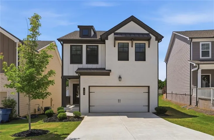 Modern two-story home featuring a white brick and vertical siding exterior, black-framed windows, an attached garage, a dormer window, and a concrete driveway
