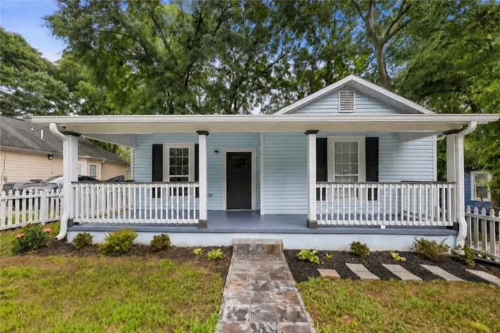 Light blue siding exterior featuring a covered porch with white railing, black front door, and black window shutters