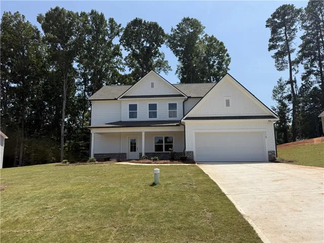 Two-story residence featuring white siding, a covered front porch, an attached two-car garage, and a concrete driveway
