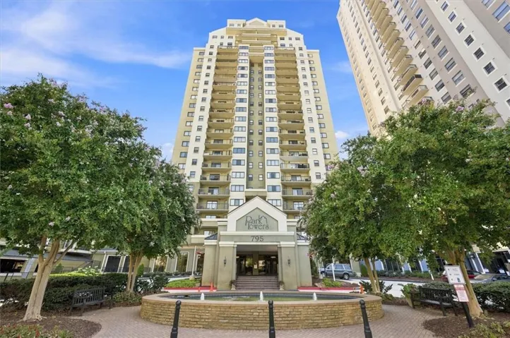 High-rise building with multiple private balconies, a prominent main entrance, and a circular fountain feature