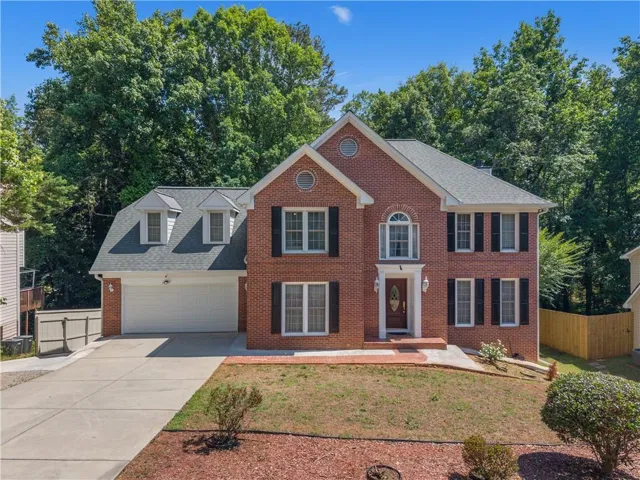 Red brick exterior with a front entry porch, arched transom window, and a two-car garage