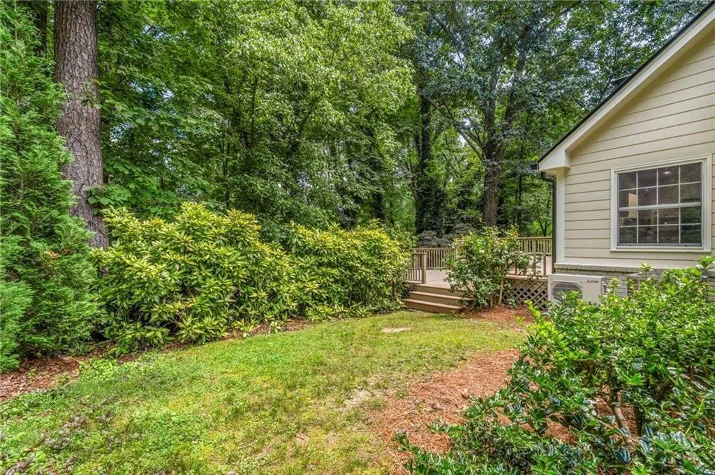 View of green lawn with a deck on the side of the home.