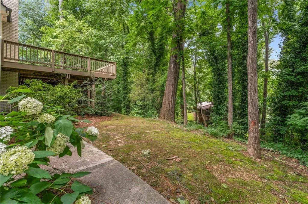 View of green lawn with a deck on the side of the home.