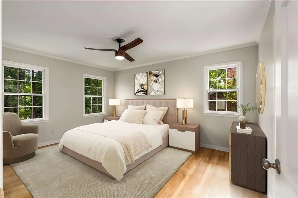 Bedroom with light wood-type flooring, multiple windows, crown molding, and a ceiling fan