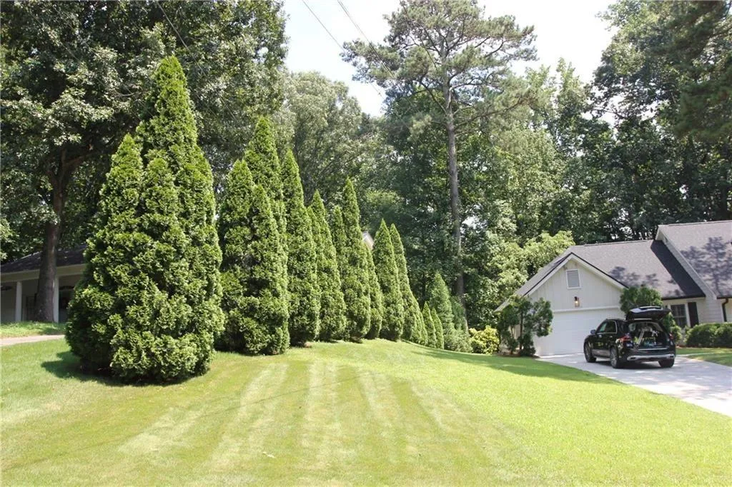 View of grassy yard featuring concrete driveway and an attached garage