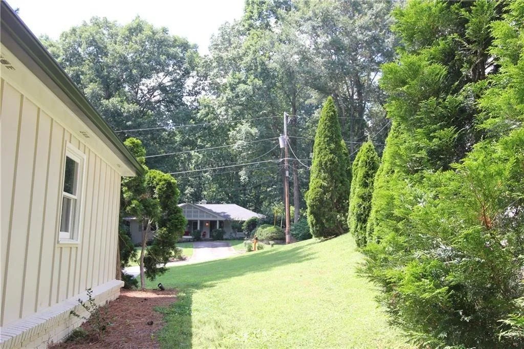 View of green lawn featuring view of wooded area