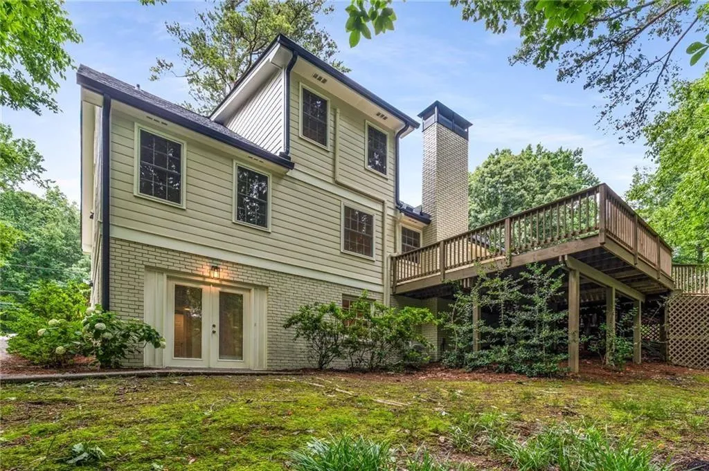 Rear view of property with brick siding, a wooden deck, french doors, and a chimney