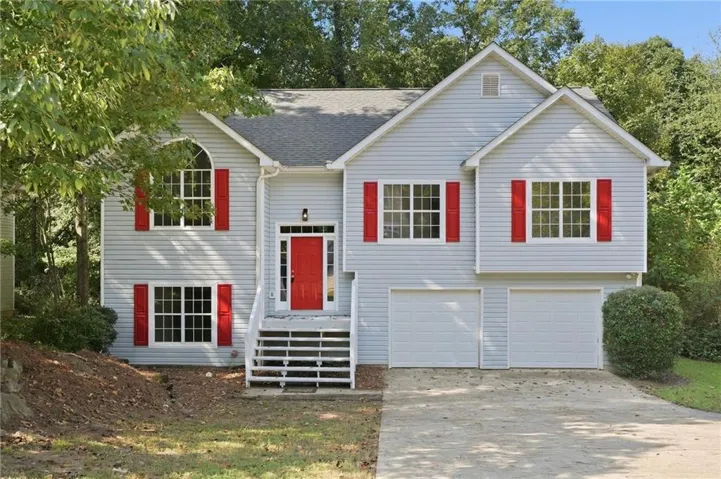 Light blue siding exterior with red shutters, a red entry door, a two-car garage, and a concrete driveway