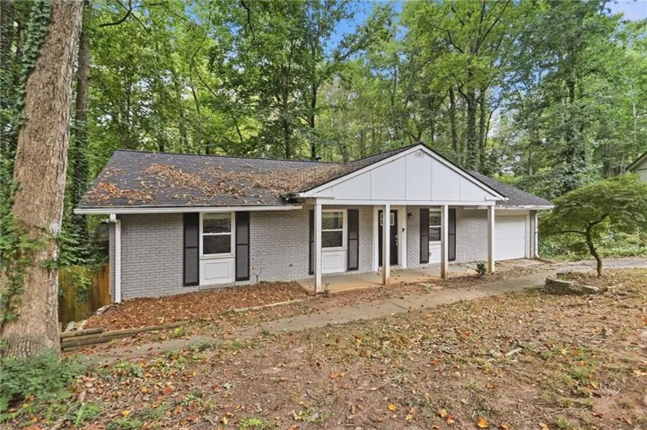 Gray brick exterior with white trim, covered front porch, and an attached single-car garage