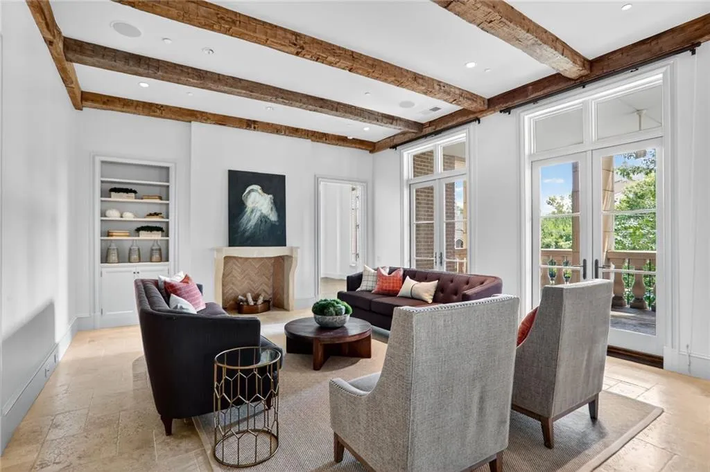 Living room with stone tile flooring, beamed ceiling, recessed lighting, built in features, and french doors