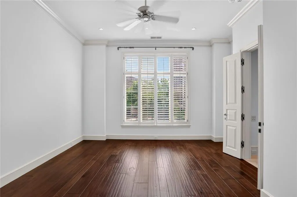 Guest Suite Bedroom 1 with abundant natural light. ornamental molding, dark wood finished engineered floors, and a ceiling fan.