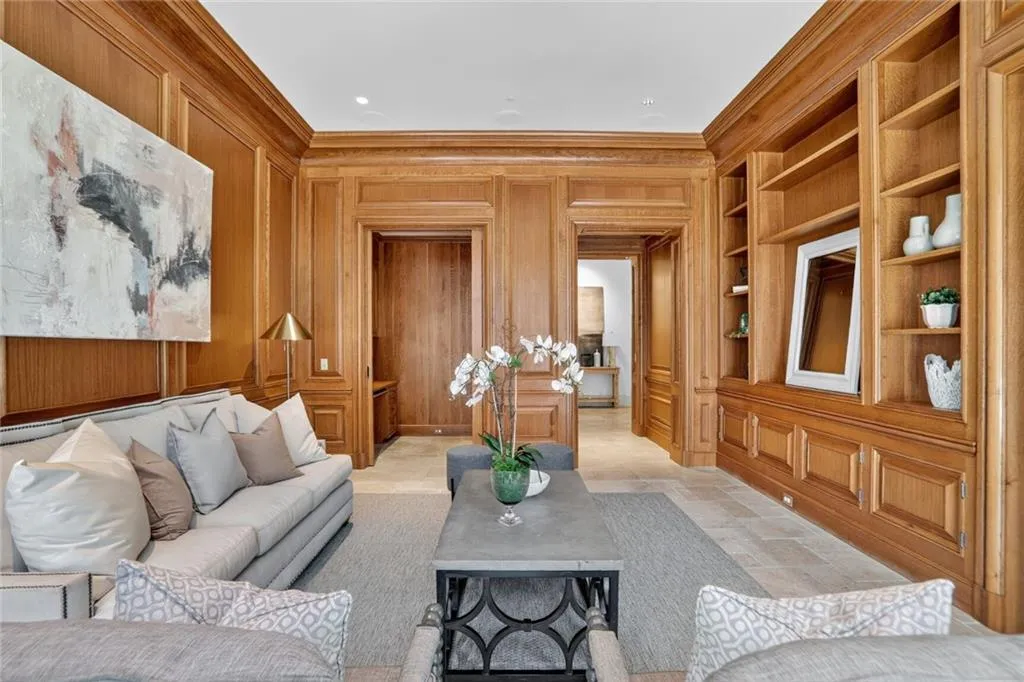 Sitting Room/Library with custom wood paneled walls, crown molding, and a hideaway office inside with pocket door.  Custom built in bookcases with tv setup.