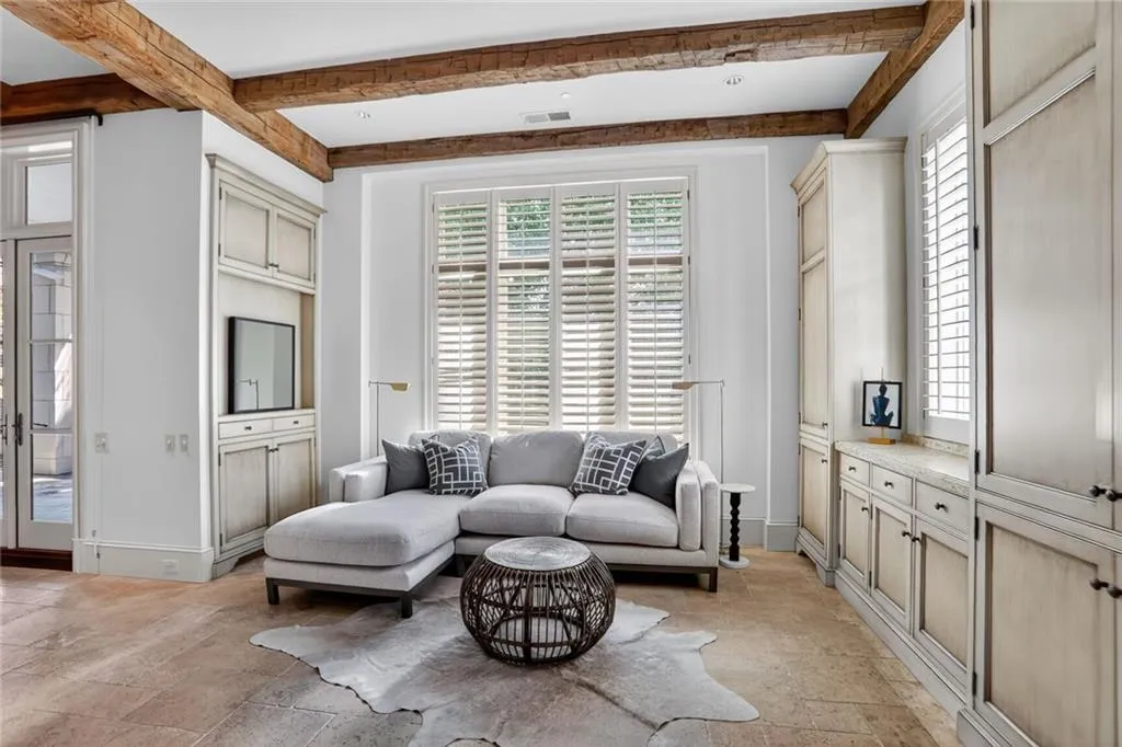 Living room with healthy amount of natural light, beam ceiling, and stone tile floors