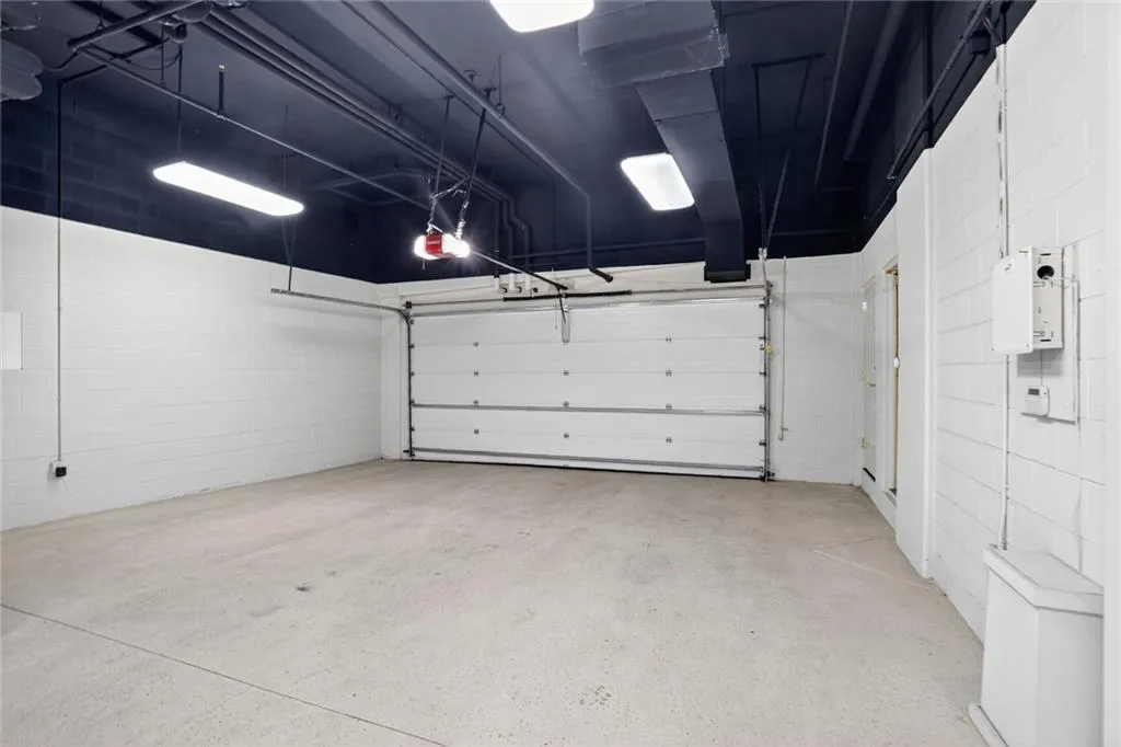Garage featuring concrete block wall and a garage door opener