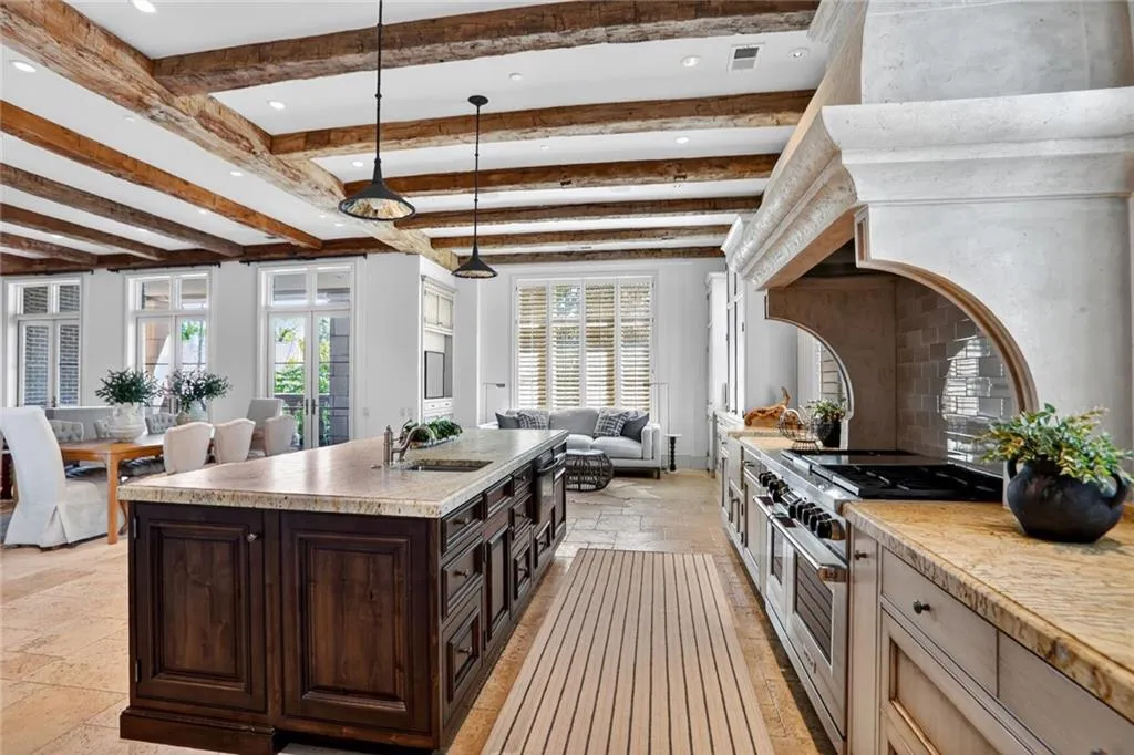 Kitchen featuring open floor plan, beam ceiling, hanging light fixtures, double oven range, and dark brown cabinetry