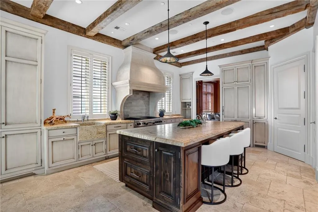 Kitchen featuring hanging light fixtures, a kitchen breakfast bar, dark brown cabinetry, an island with sink, and stone tile flooring