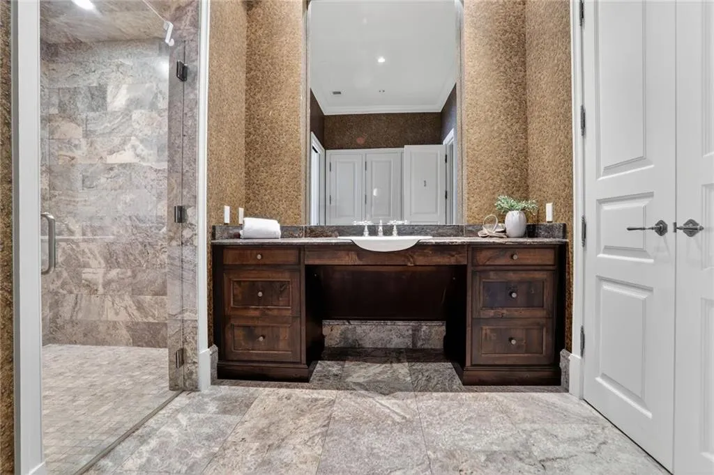 Bathroom with a stall shower, vanity, a closet, and crown molding