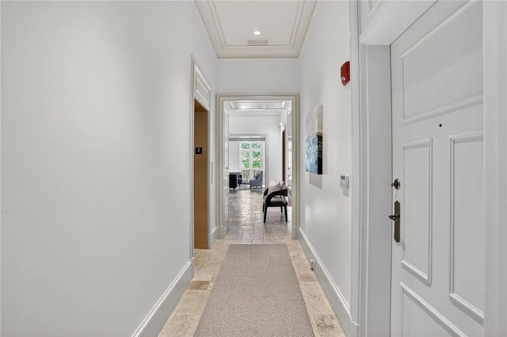 Hall with stone tile floors, crown molding, and attic access