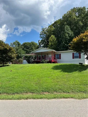 White siding exterior with red-trimmed windows and a covered front porch