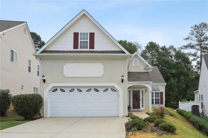 Exterior featuring stucco and siding finishes, an attached two-car garage with transom windows, a covered front entry, and mature landscaping