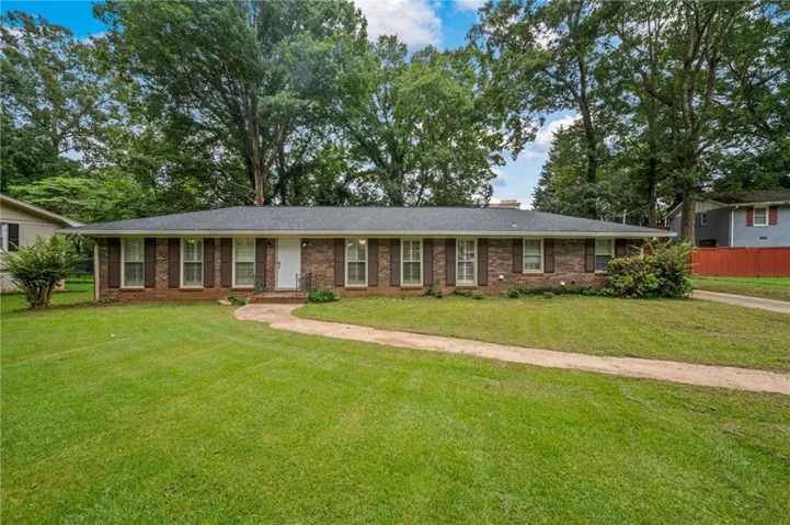 Ranch-style home featuring a front lawn, brick siding, and a chimney