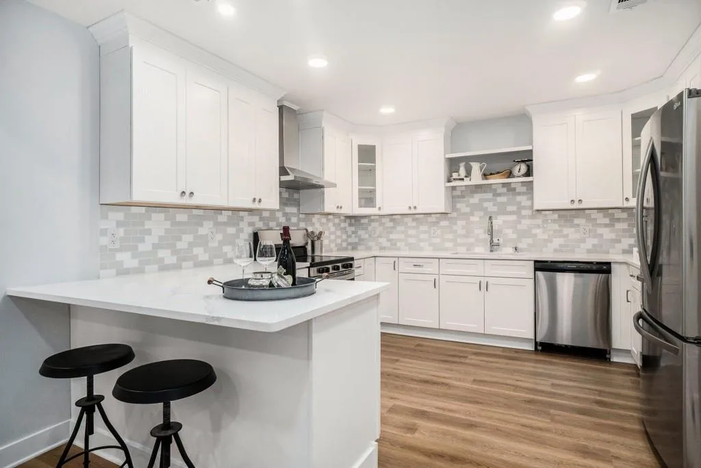 The Kitchen has been Fully Updated with White Shaker Cabinets to the Ceiling, Quartz Countertops, a Tiled Backsplash, Breakfast Bar, and Stainless Steel Appliances.