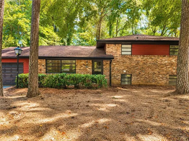 Brick facade with red siding accents, attached garage, and multi-pane windows